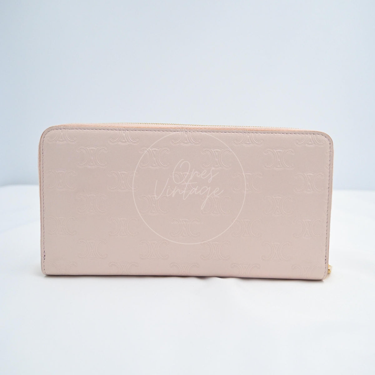 Celine Triomphe Embossed Calfskin Zippy Long Wallet in pink lambskin, featuring zipper closure and embossed monogram pattern, front view