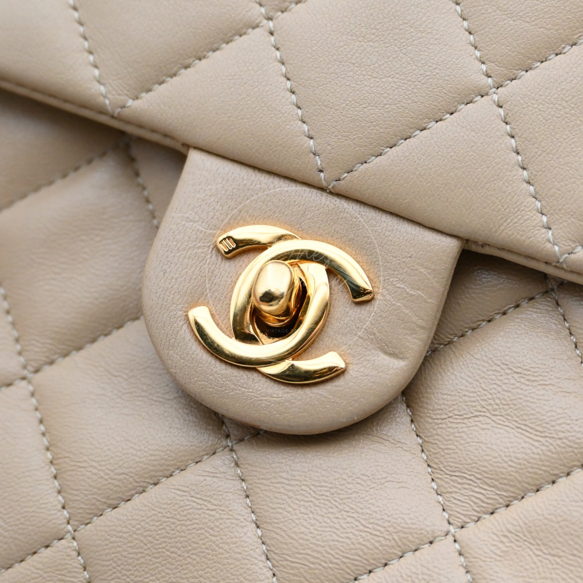 Close-up of Chanel vintage gold-plated CC turn-lock on beige leather