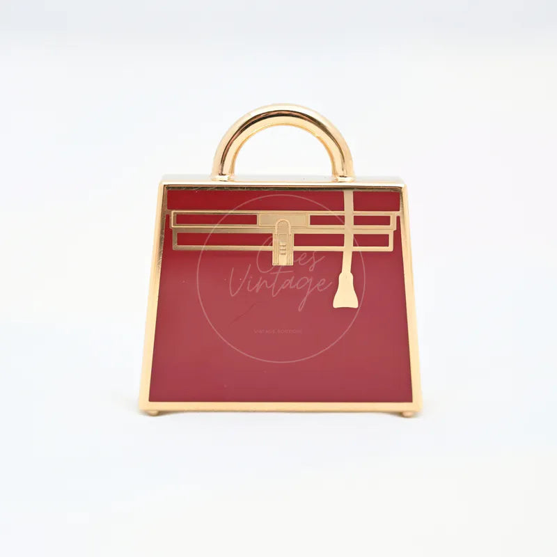 Hermès Kelly Charm and in red and gold alloy metal, featuring central clasp and arched top handle, front view