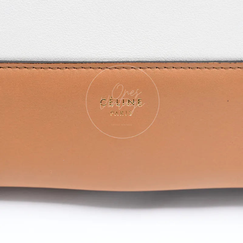 Close-up of gold foiled CÉLINE PARIS logo stamp on tan and white leather