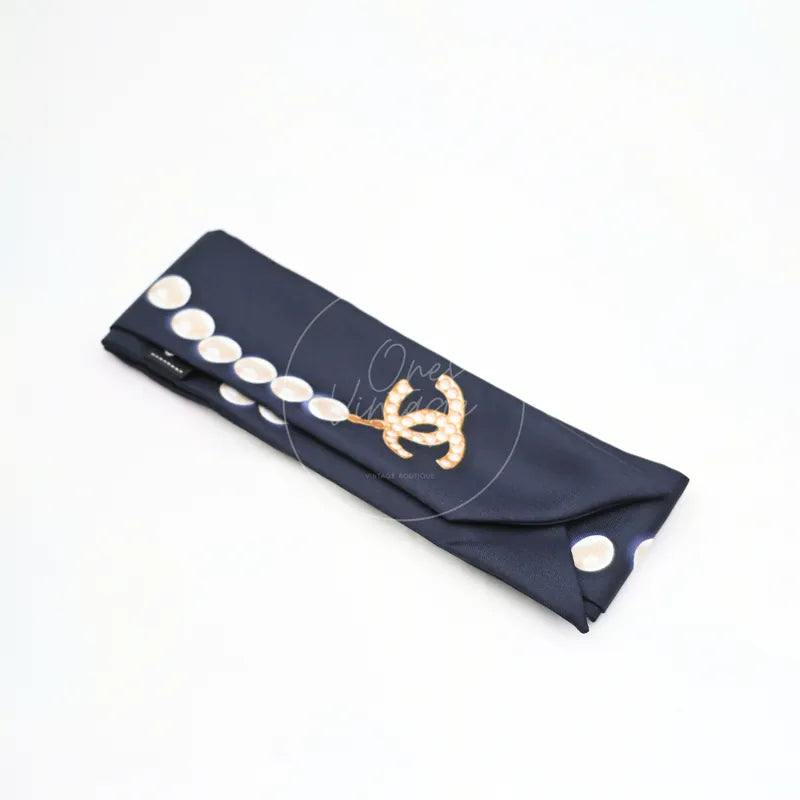 Chanel Slim Bandeau Twilly in black silk, featuring polka-dot print and interlocking CC motif, front three-quarter view