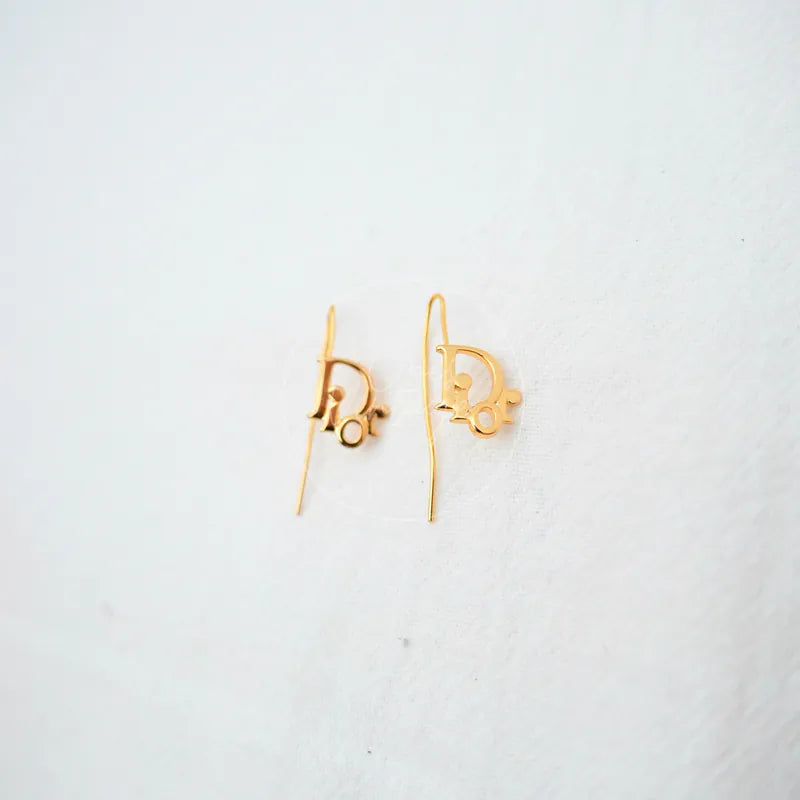 Dior Logo Drop Earrings in gold plate, featuring logo-shaped drop earrings and slender wire hooks, front view
