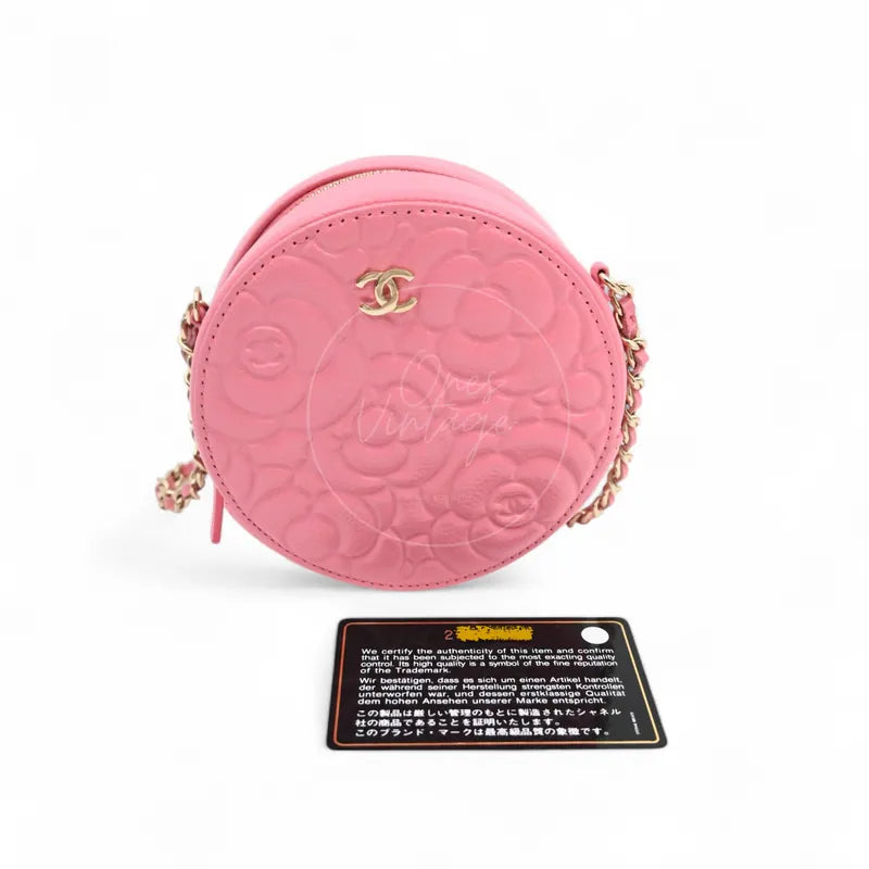 Chanel round clutch bag in pink camellia-embossed caviar leather with gold hardware, Series 29, front view with authenticity card