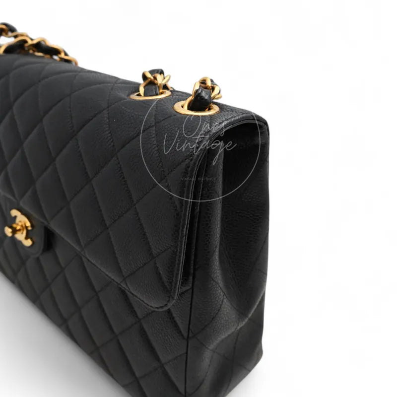 Chanel Jumbo Classic Flap Bag in black caviar with gold-tone hardware, featuring chain strap and gold-tone grommets, front three-quarter view