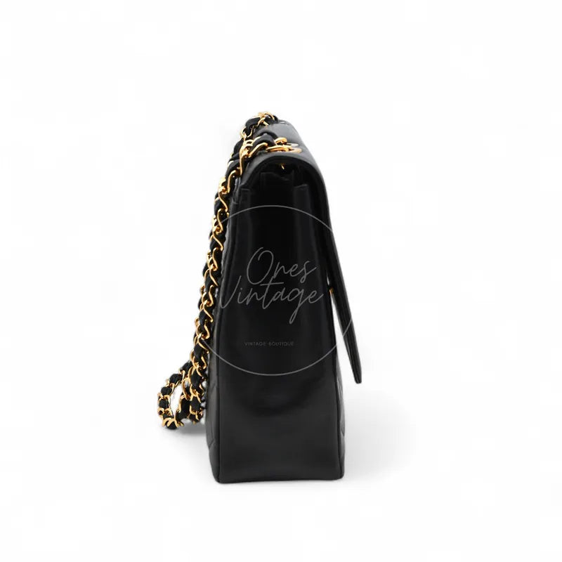 Chanel Vintage Maxi CC Straight Flap Bag in black lambskin, featuring structured side panel with interwoven chain shoulder strap, left side view