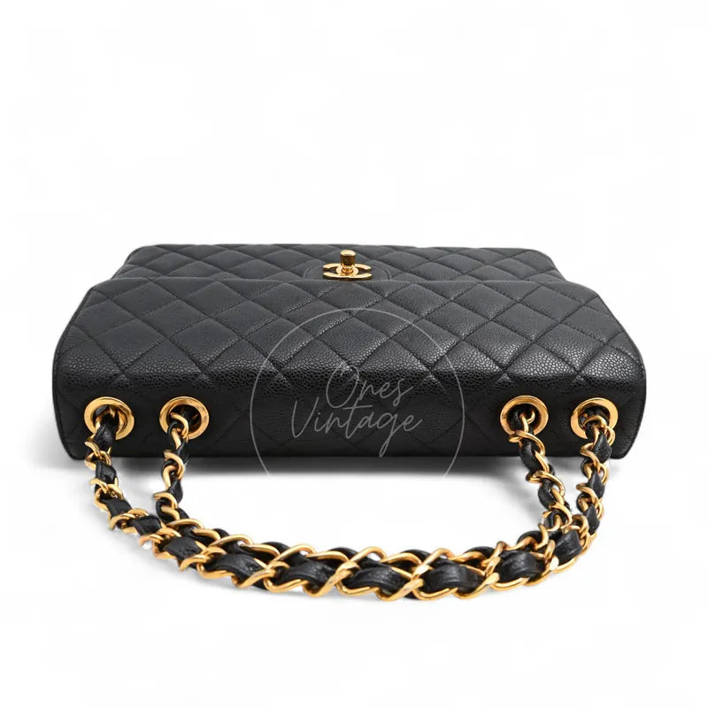 Chanel Jumbo Classic Flap Bag in black caviar with gold-tone hardware, featuring woven chain strap and turn-lock clasp, front view