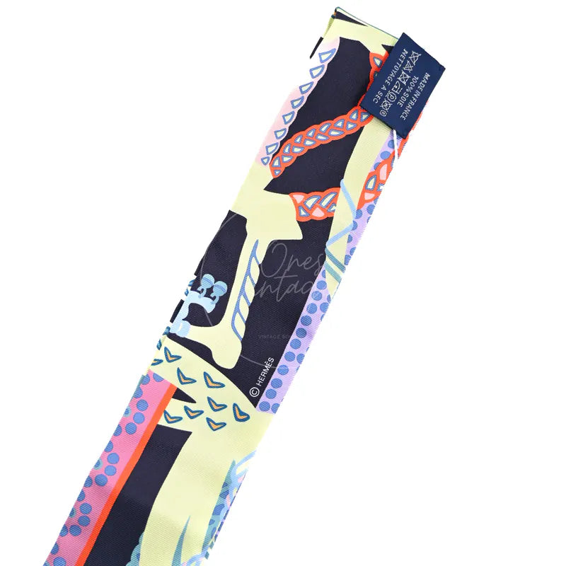 Hermès Fantaisie d'Etriers Twilly in marine, mauve and jaune soufre silk 100%, featuring equestrian-inspired print, front view