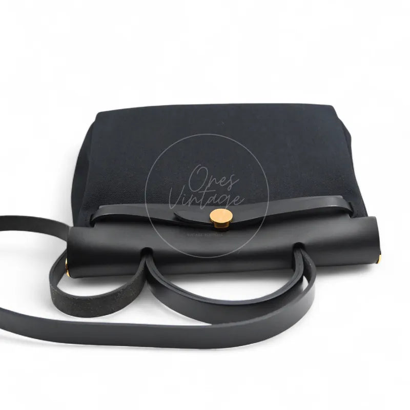 Hermès Herbag Zip 31 Canvas in black toile canvas and swift with gold-tone hardware, featuring gold-tone clasp and canvas flap, front view