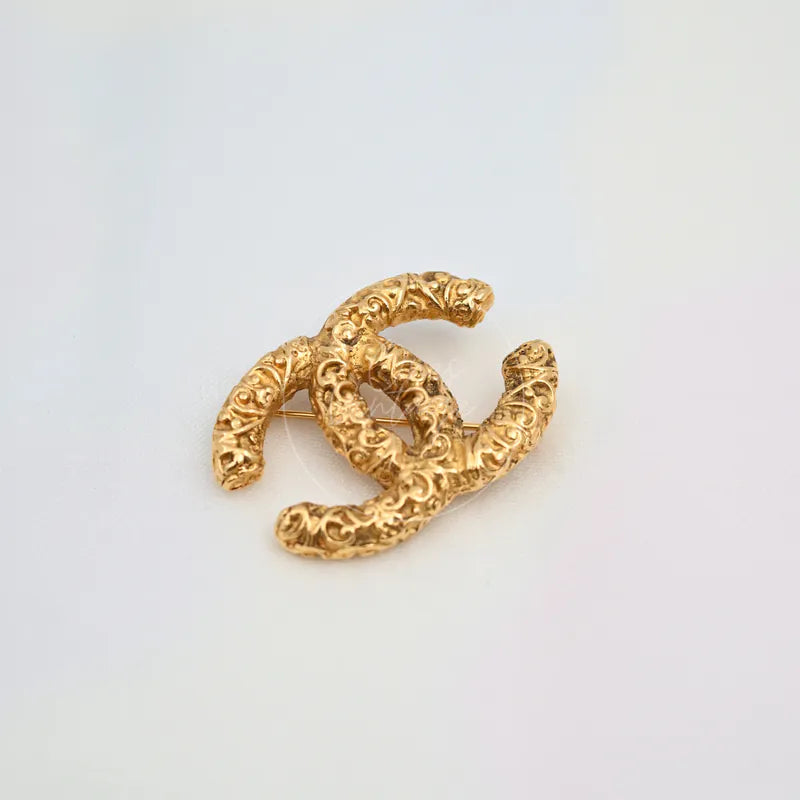 Chanel Vintage CC Mark Brooch in 24K gold-plated, featuring interlocking CC motif and ornate raised relief, front view