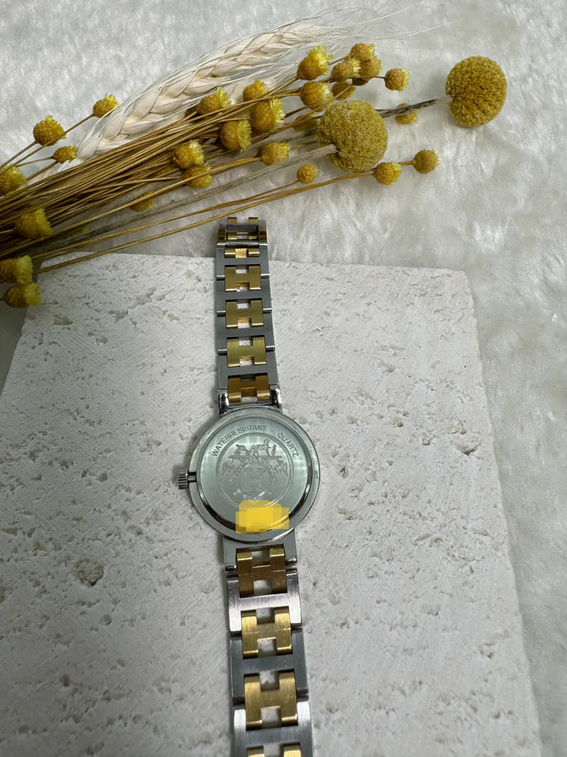 Hermès Classic Clipper watch in stainless steel and gold-plated, featuring circular caseback and engraved perimeter text, back view
