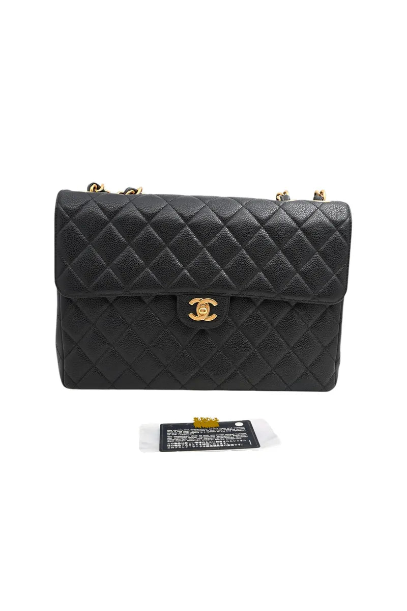 Chanel Jumbo Classic Flap Bag in black caviar, featuring gold-tone CC turn-lock clasp and chain links visible at top, front view