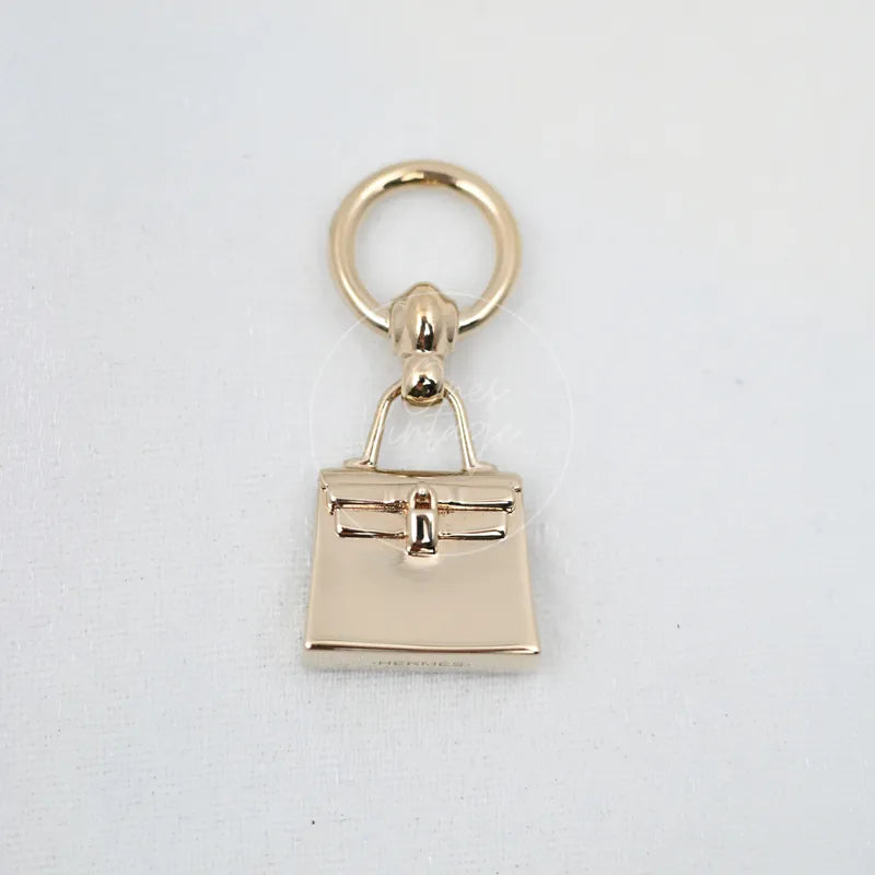 Hermès Plated Mini Kelly Twilly Scarf Ring in gold-plated metal, featuring central bar closure and miniature handbag silhouette, front view