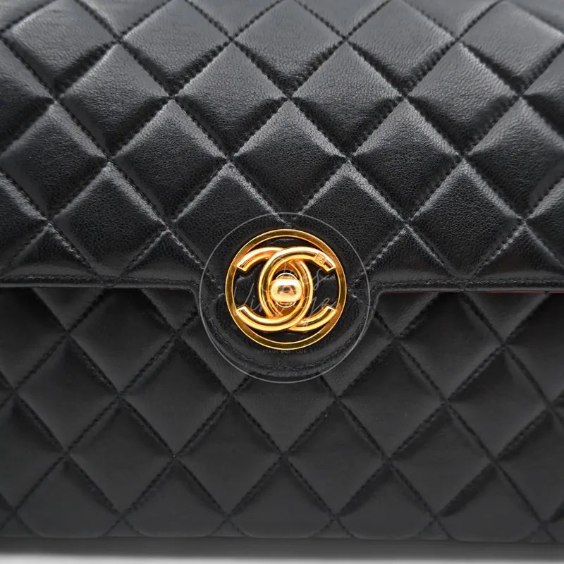 Close-up of vintage gold-plated round interlocking CC turn-lock hardware on black lambskin leather