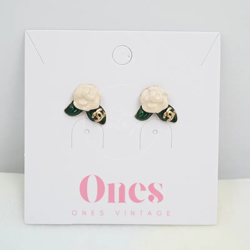 Chanel Camellia Baramotif Stud Earrings in gold-plated metal and enamel, featuring white floral motifs and green leaf-shaped accents, front view
