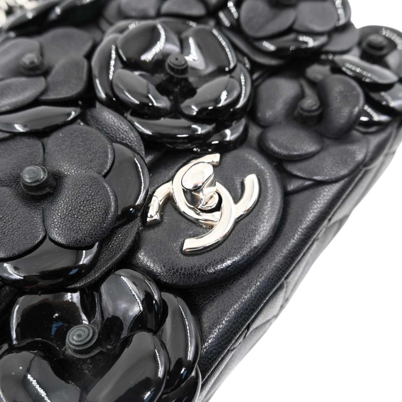 Close-up of Chanel silver-tone CC turn-lock and leather camellia flowers