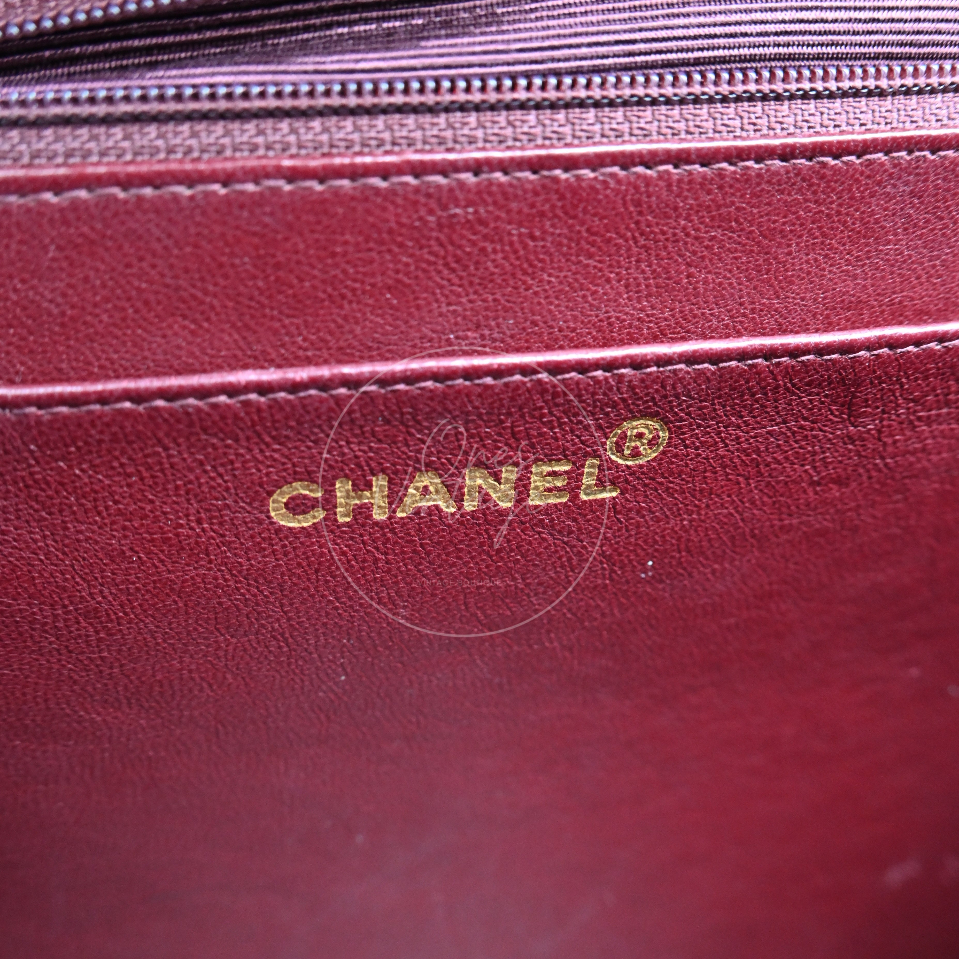 Gold foil CHANEL logo stamp inside the burgundy leather lining of a vintage bag