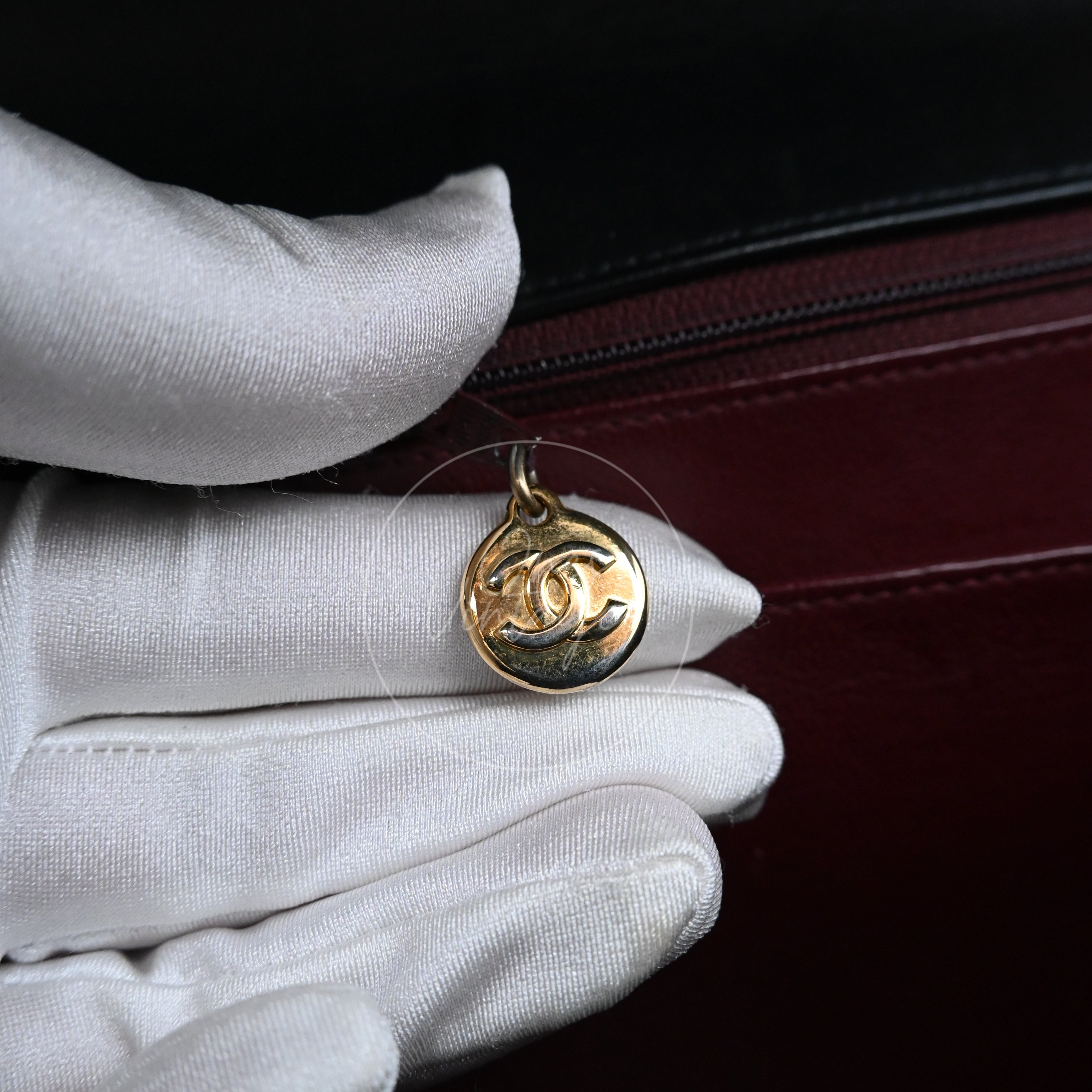 Close-up of vintage gold-tone round zipper pull with CC logo inside Chanel bag