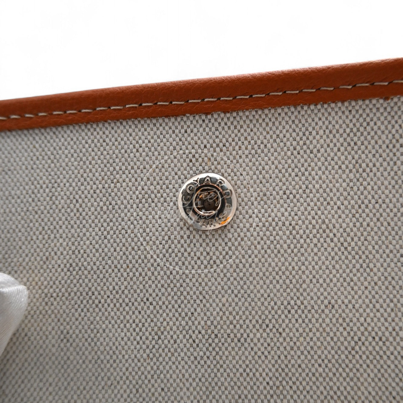 Close-up of engraved GOYARD PARIS silver-tone snap button fastener inside flap