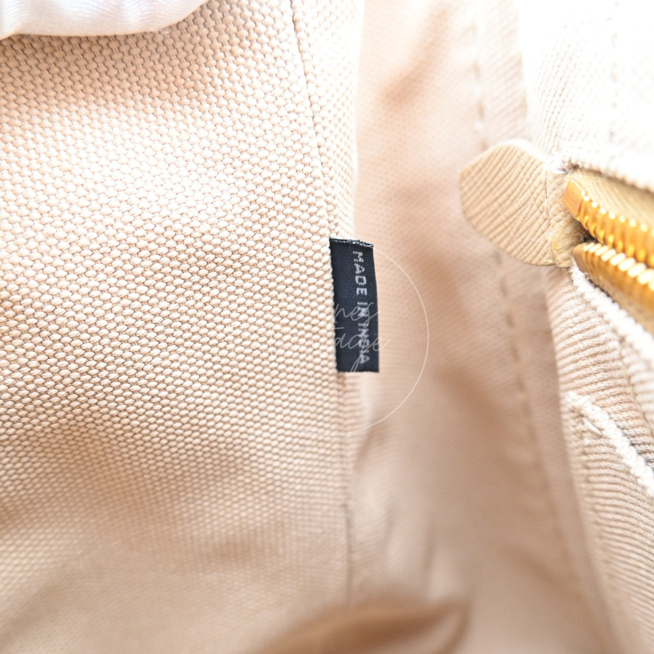Close-up of black factory location tag printed with MADE IN INDIA inside Prada bag