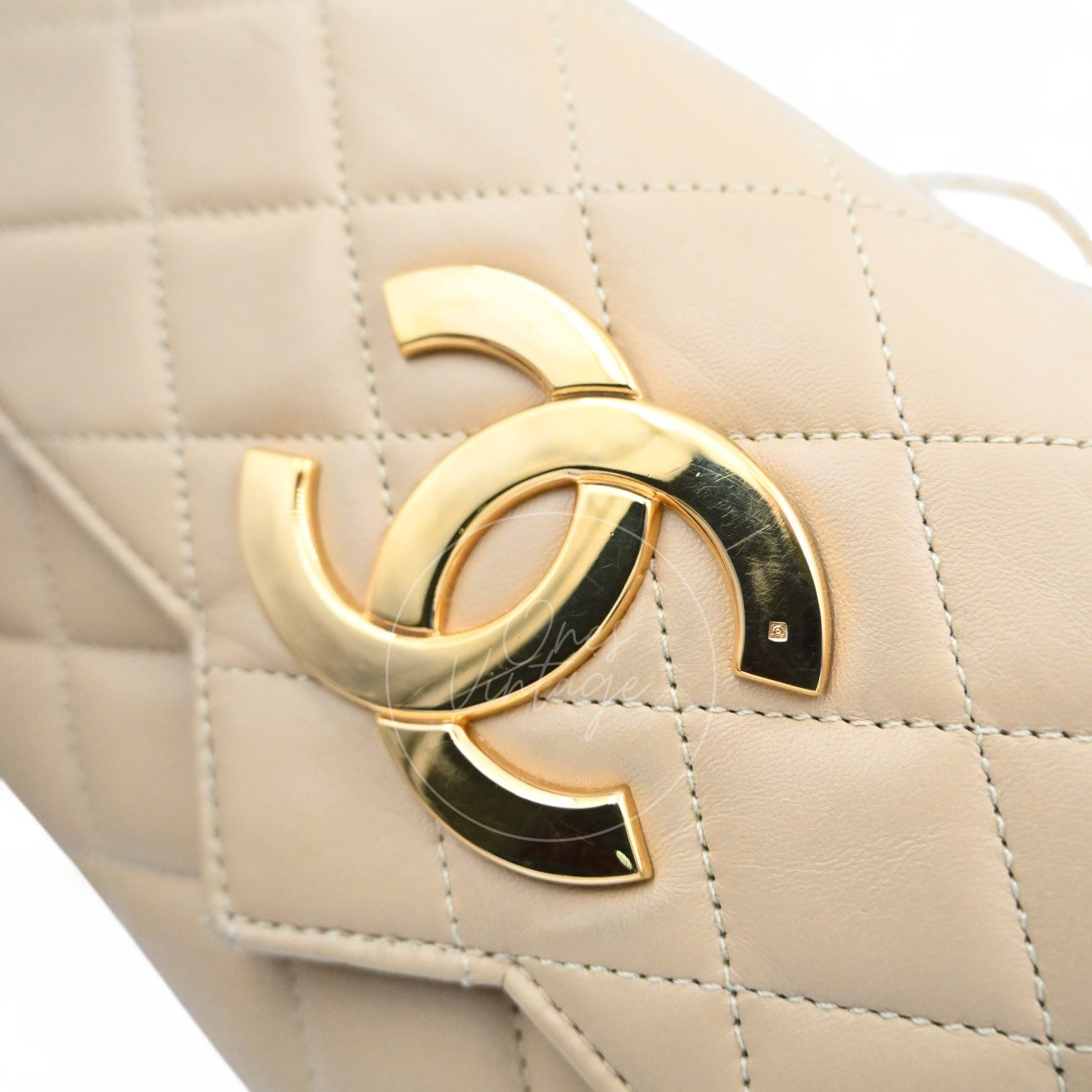 Close-up of Chanel vintage 24k gold-plated oversized CC turn-lock on beige leather