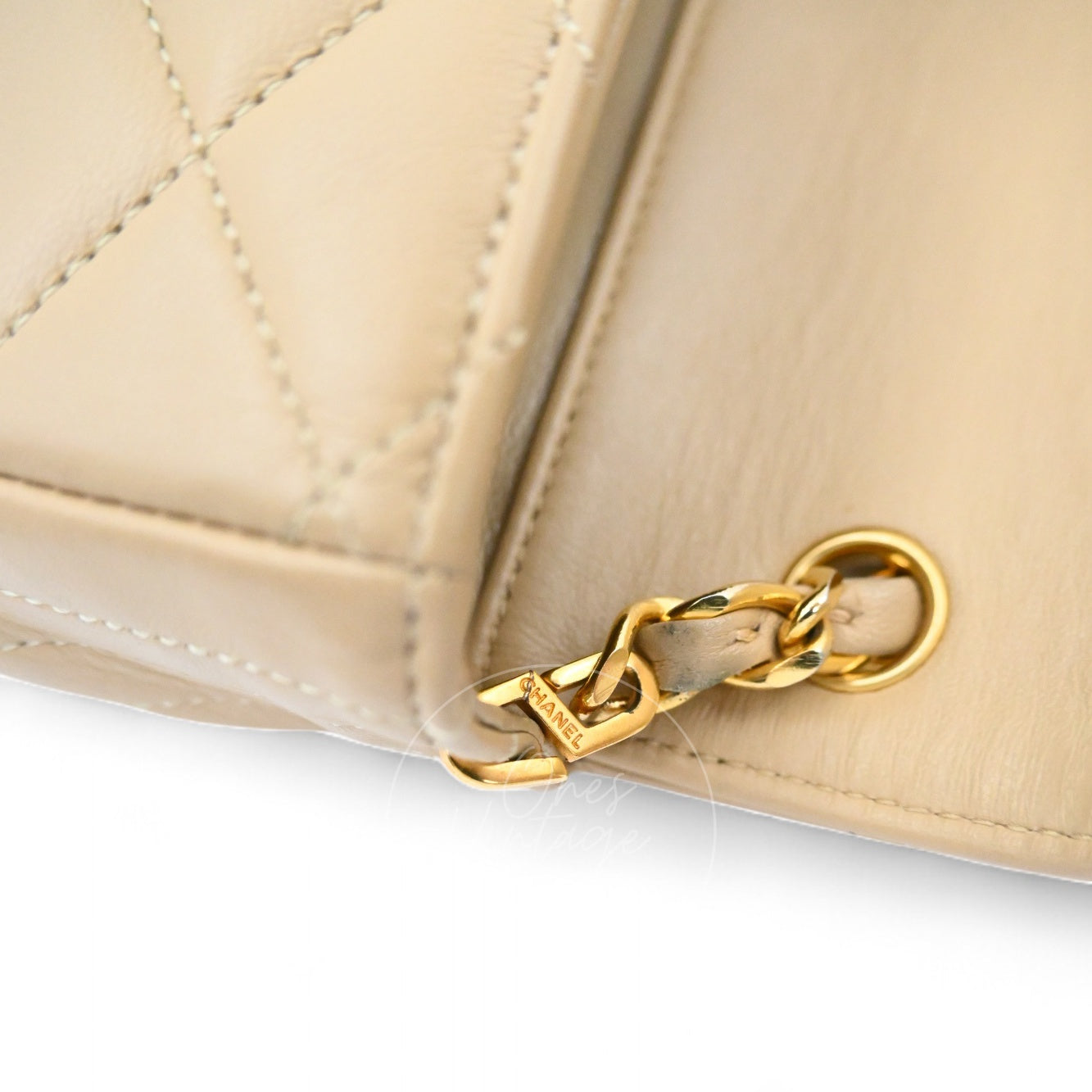 Close-up of engraved CHANEL logo on the strap eyelet hardware of beige vintage bag