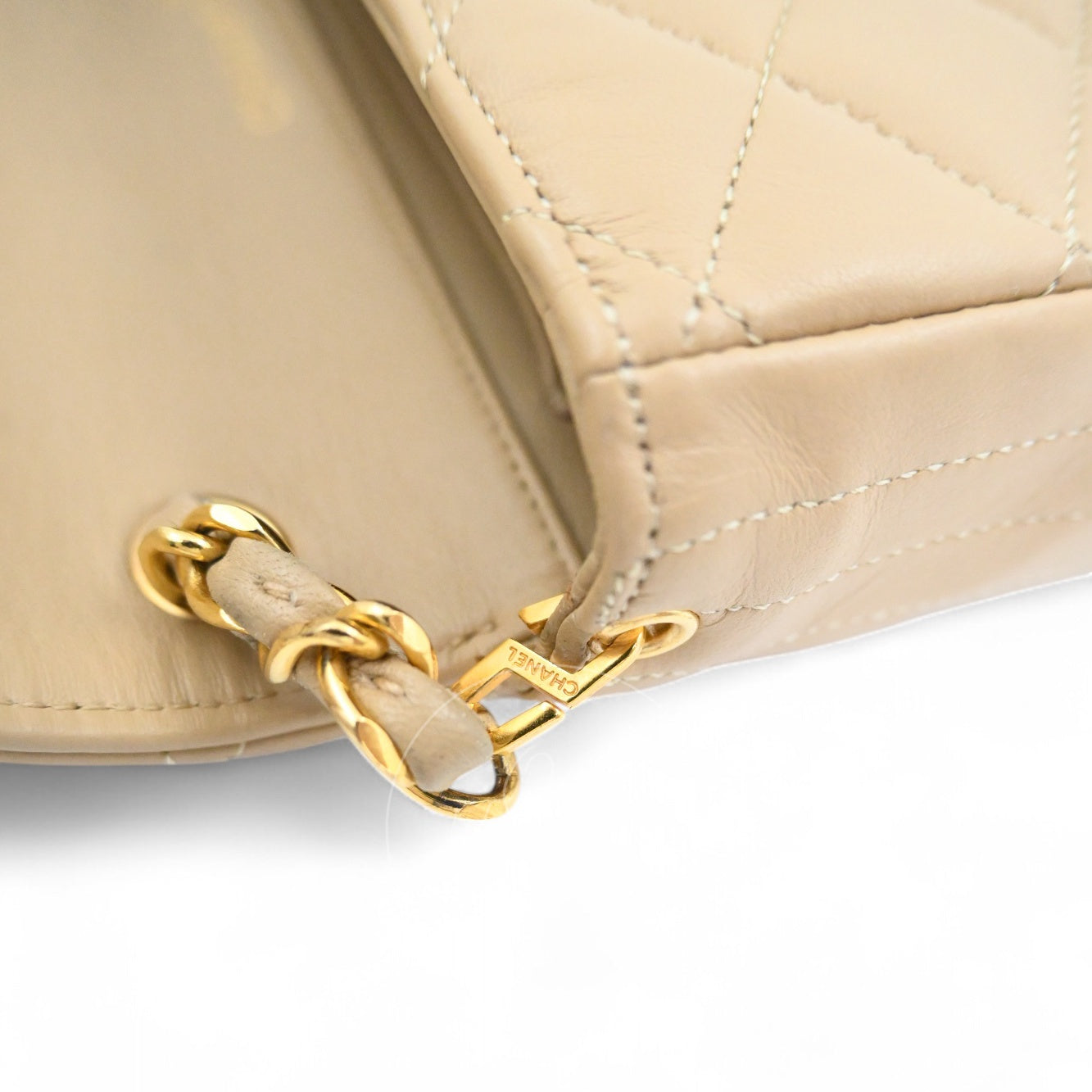 Close-up of engraved CHANEL logo on the strap eyelet hardware of beige vintage bag