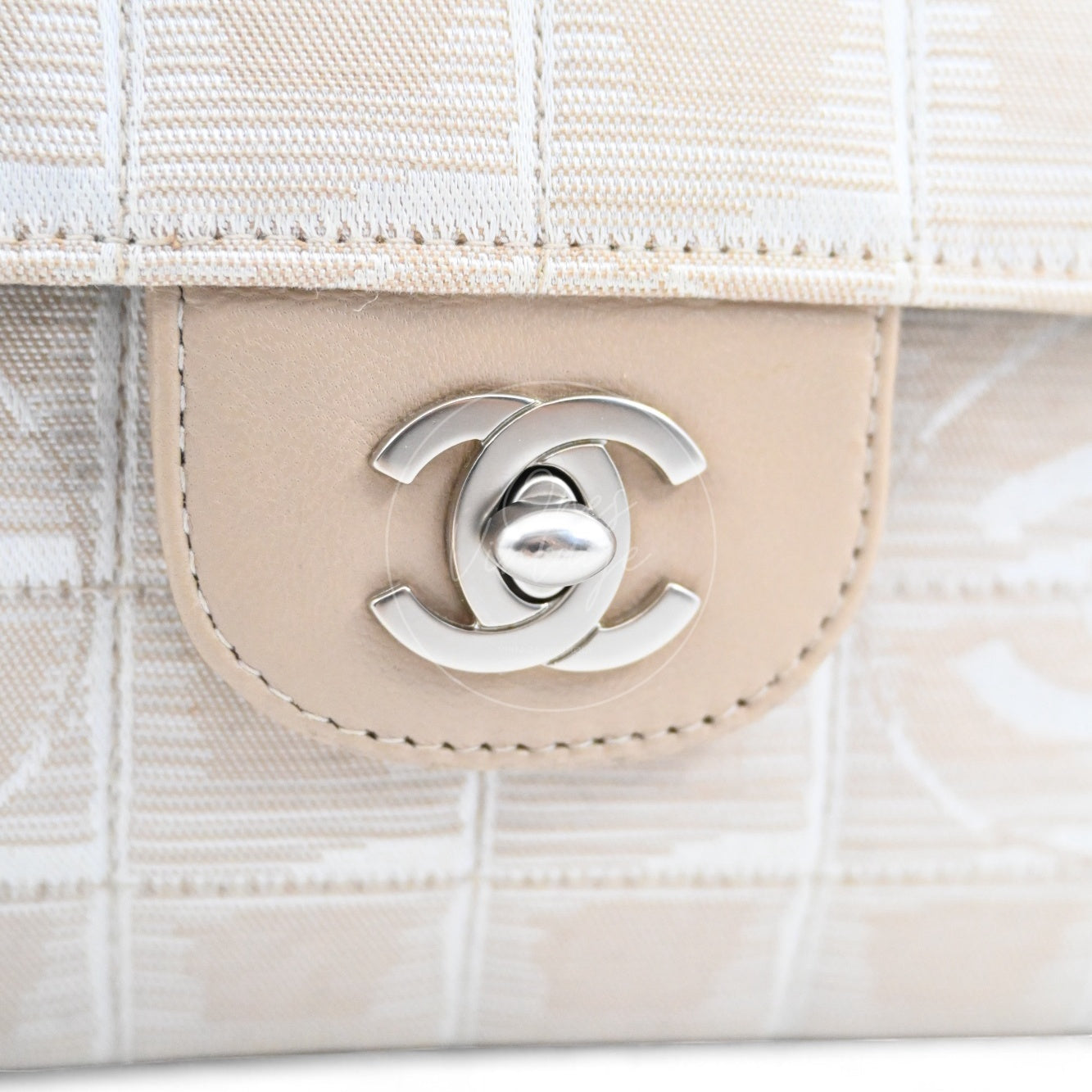 Close-up of Chanel New Travel Line matte silver CC turn-lock and beige jacquard canvas