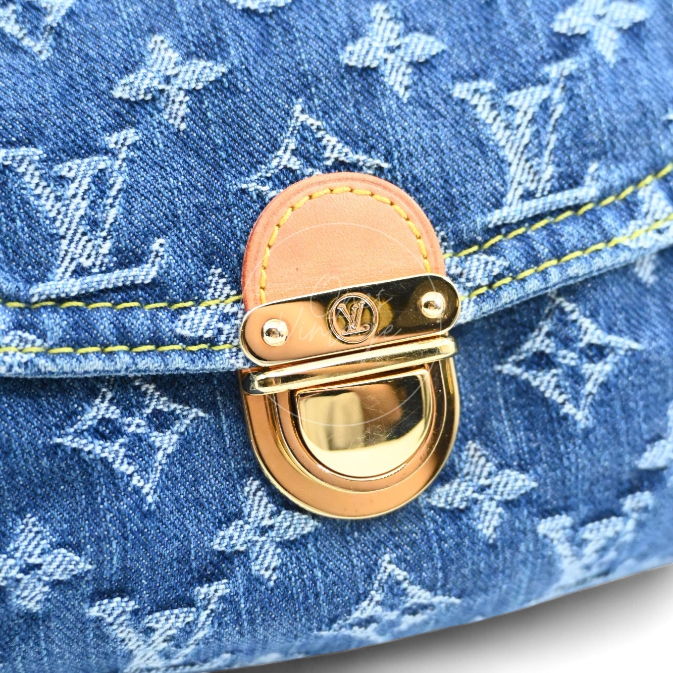 Close-up of Louis Vuitton vintage denim bag gold-tone hardware push-lock and vachetta leather trim