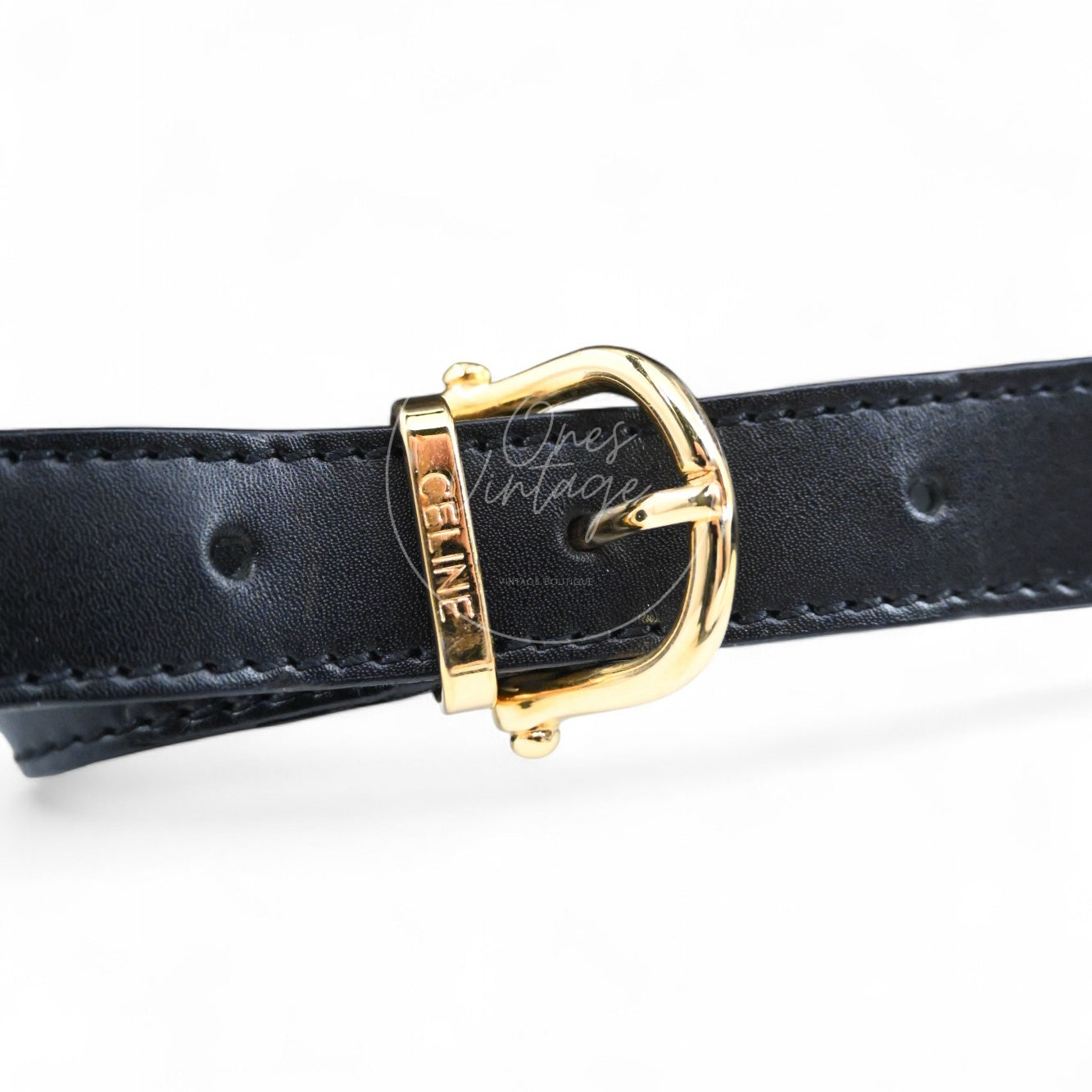 Close-up of gold-tone belt buckle engraved with CELINE on black leather backpack strap