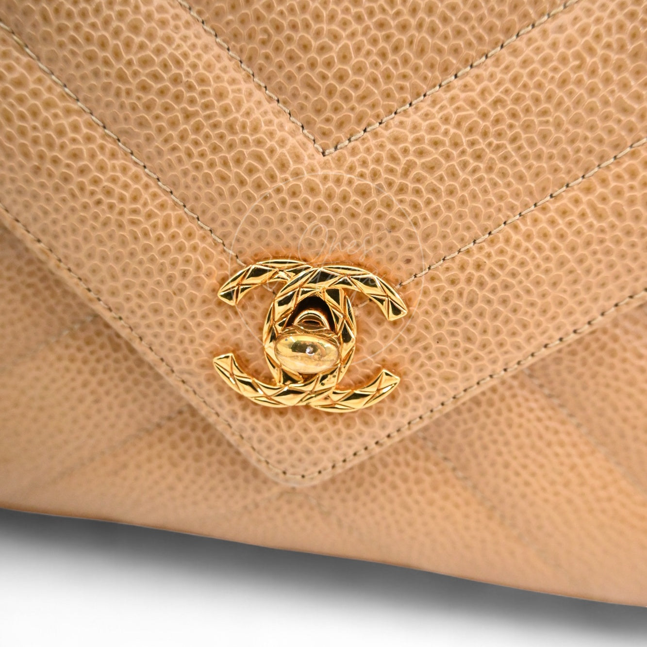 Close-up of textured gold-tone interlocking CC turn-lock hardware on Caviar Chevron leather