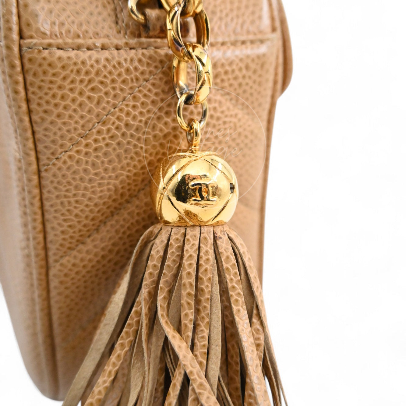 Close-up of vintage Chanel gold ball with CC logo and leather tassel charm detail
