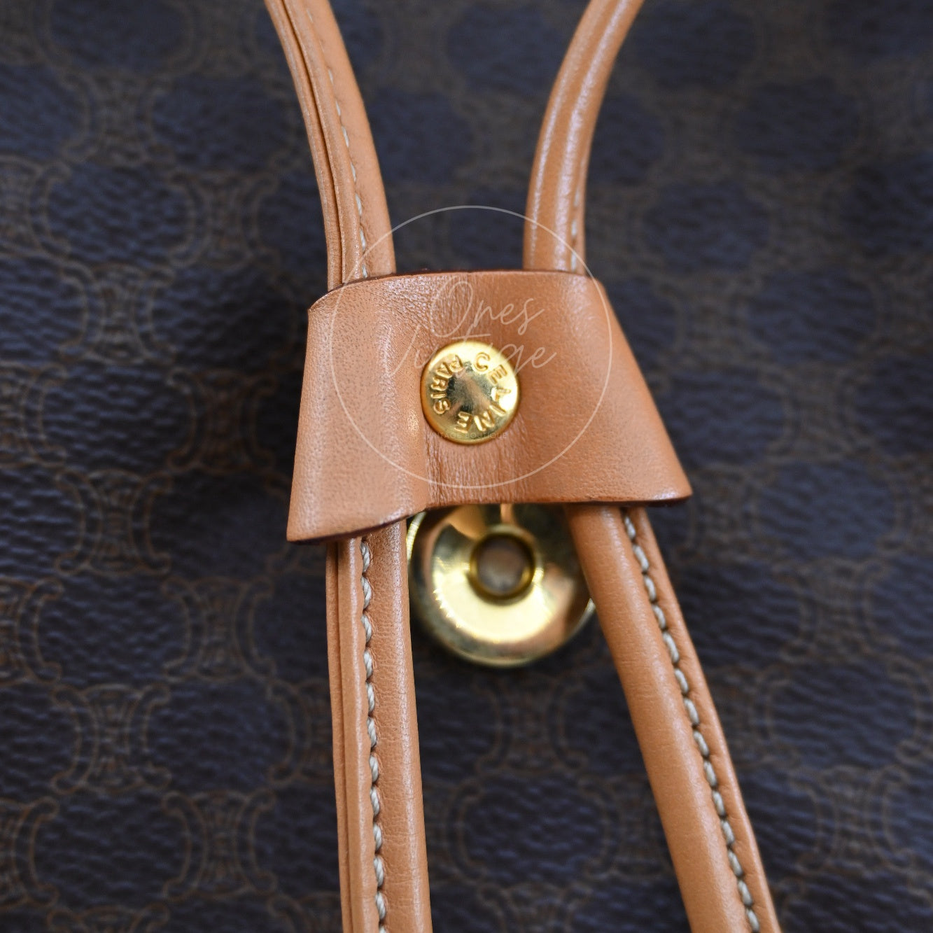 Close-up of gold-tone magnetic snap and engraved CELINE PARIS metal rivet on leather strap