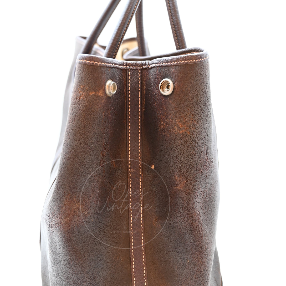 Hermès Garden Party 36 Amazon tote in dark brown rubber with leather trim, close-up of side panel surface wear and snap fastener