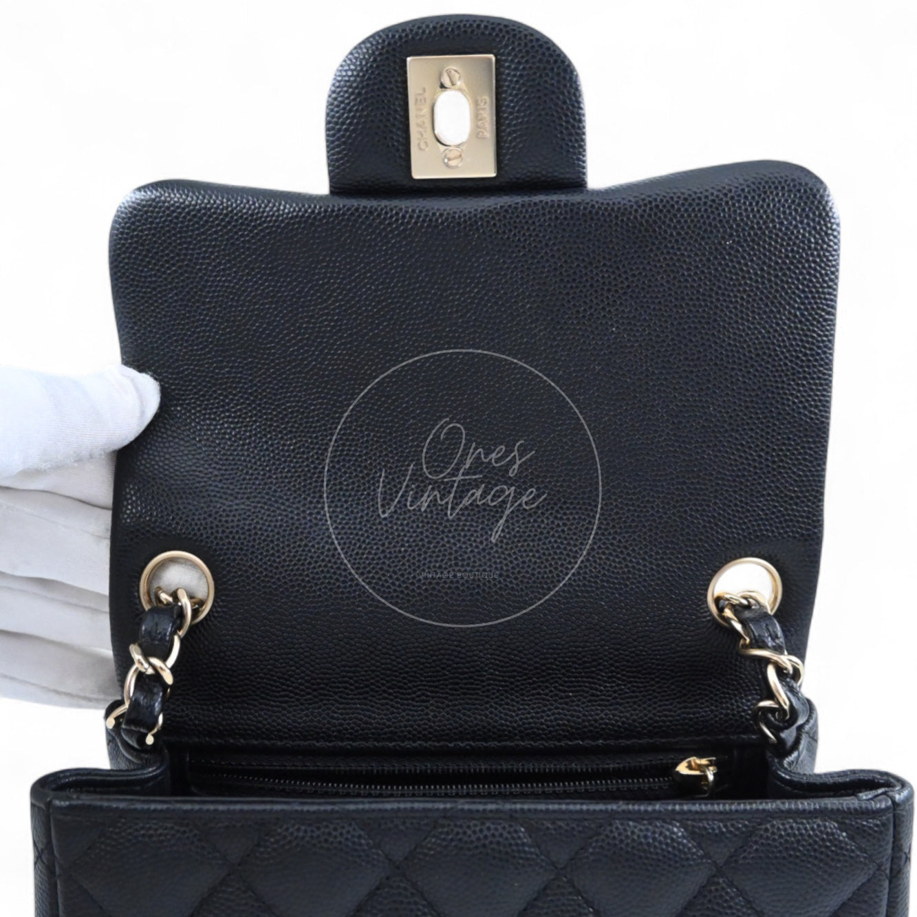 Open view of Chanel classic mini bag showing black interior lining and light gold-tone chain grommets