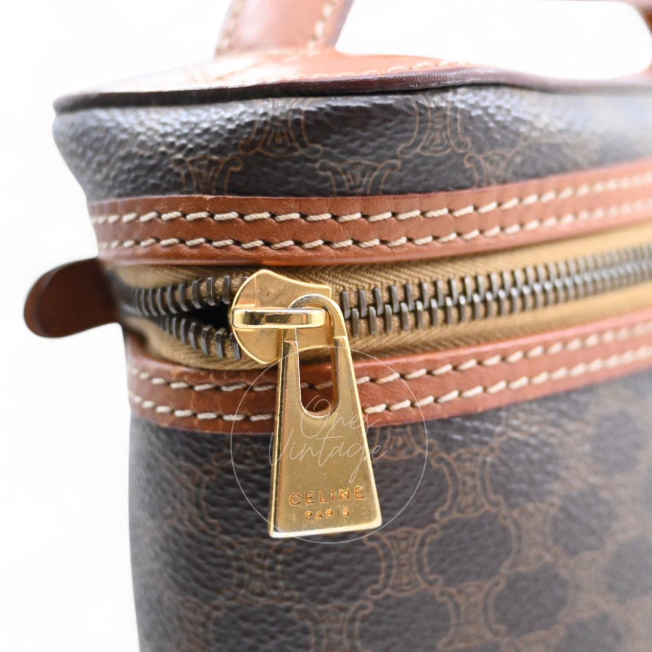 Close-up of vintage gold-tone zipper pull engraved with CELINE PARIS logo on a macadam bag