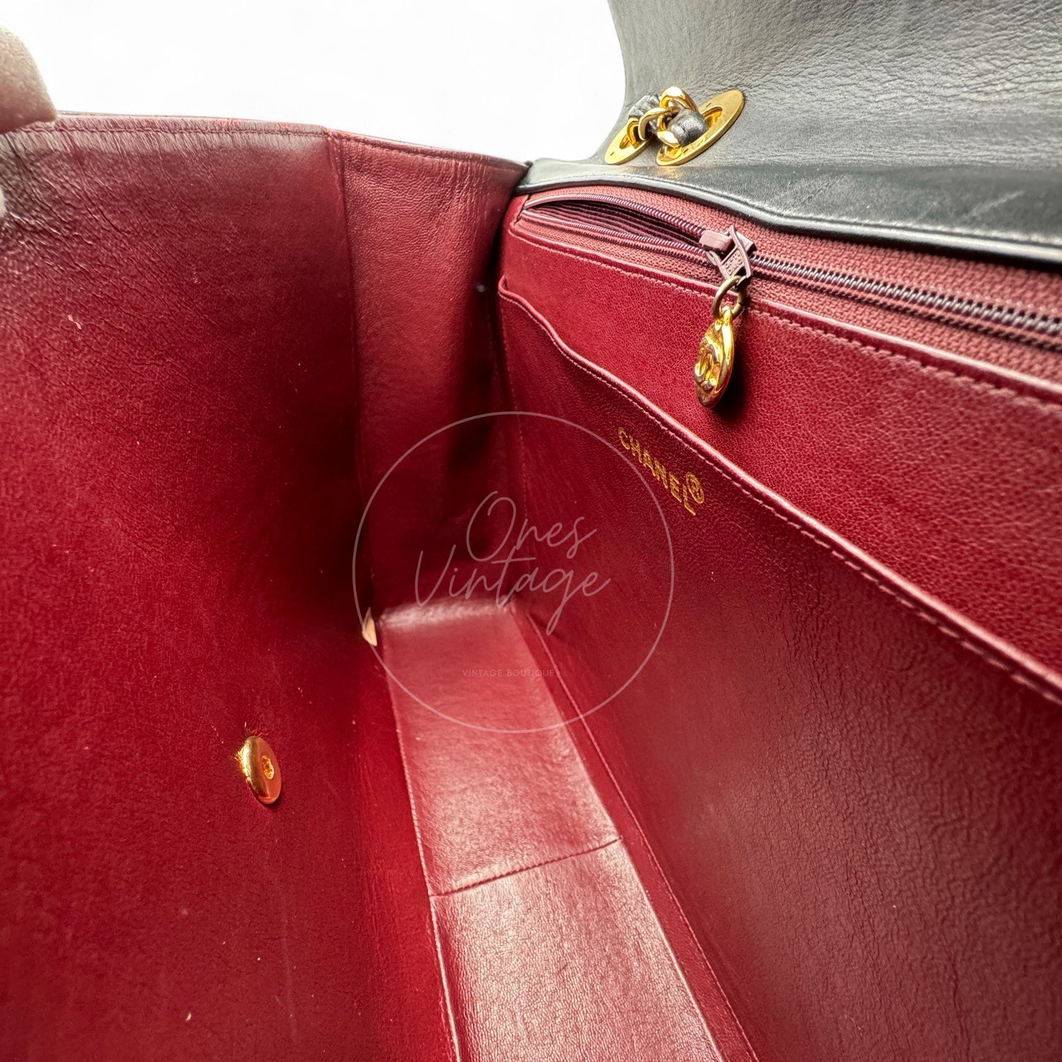 Interior view of open Chanel vintage bag showing burgundy leather lining and zipper pocket