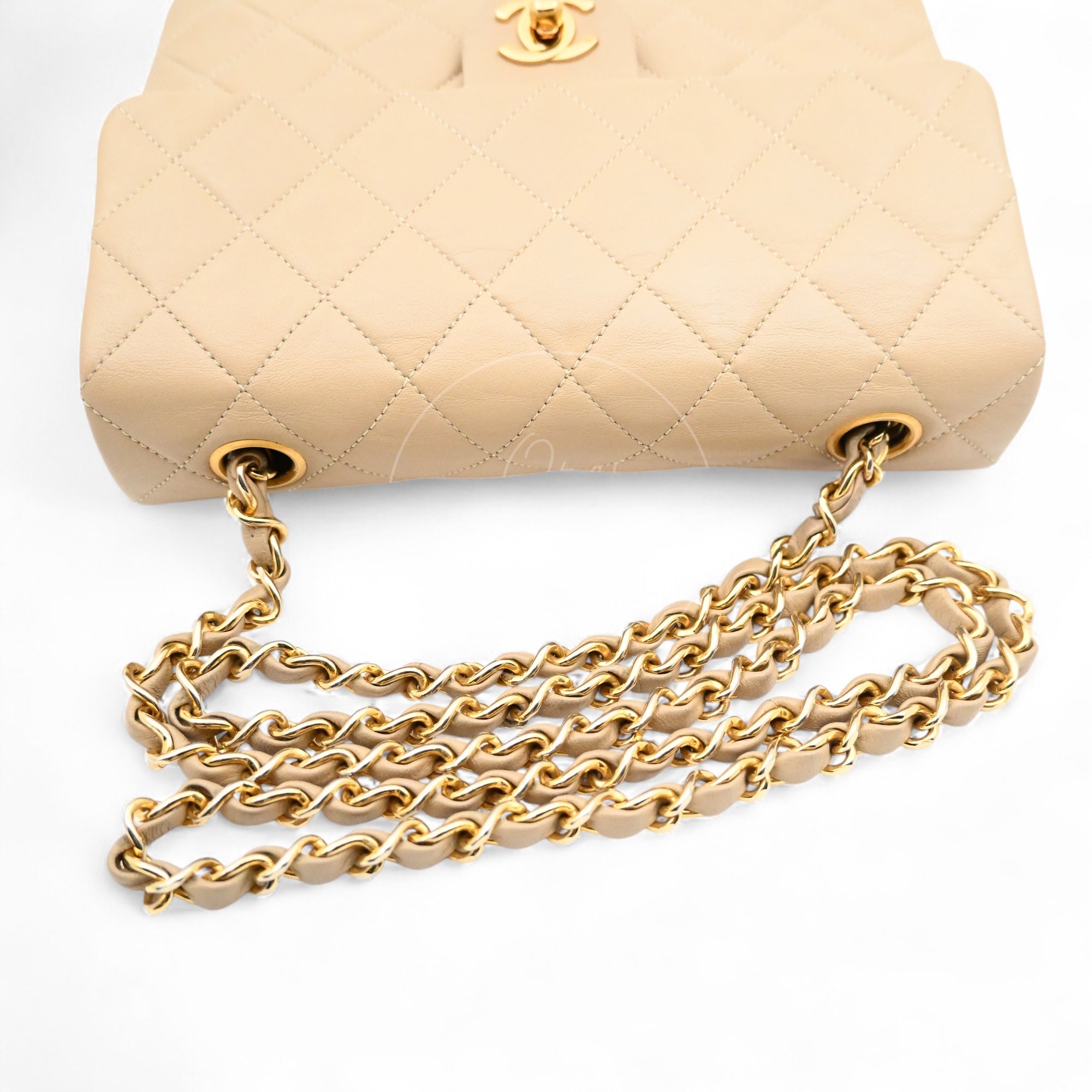 Top view of Chanel vintage classic flap bag in beige lambskin showing gold-tone grommets and interwoven chain strap